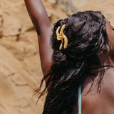 Woman with a gold hair accessory against a beige stone wall
