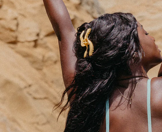 Woman with a gold hair accessory against a beige stone wall