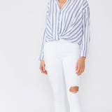 Woman wearing a blue and white striped shirt and white pants on a white background