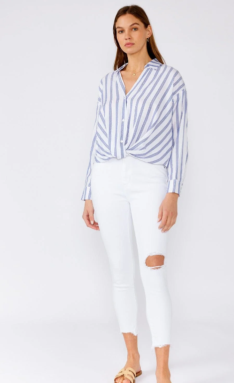 Woman wearing a blue and white striped shirt and white pants on a white background