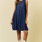 Woman wearing a blue dress and white cowboy boots on a beige background