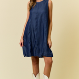 Woman wearing a blue dress and white cowboy boots on a beige background