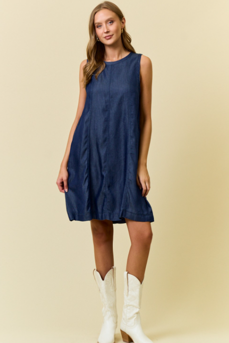 Woman wearing a blue dress and white cowboy boots on a beige background