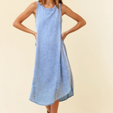 Woman wearing a light blue denim dress on a beige background