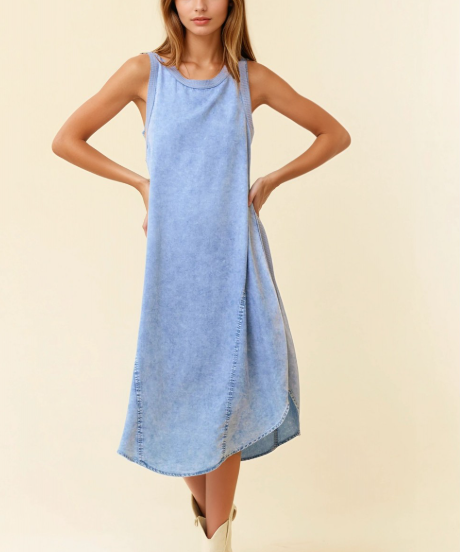 Woman wearing a light blue denim dress on a beige background