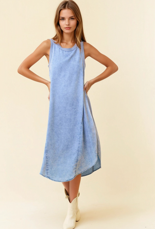 Woman wearing a light blue denim dress on a beige background