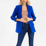 Woman wearing a blue blazer over a beige top and blue jeans on a white background