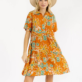 Woman wearing an orange floral dress with a white background