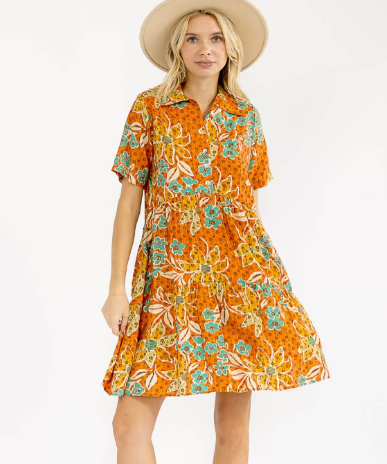 Woman wearing an orange floral dress with a white background