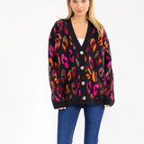 Woman wearing a colorful leopard print cardigan on a white background