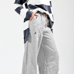 Person wearing a black and white striped shirt with high-waisted, wide-leg pants on a white background