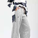 Person wearing a black and white striped shirt with high-waisted, wide-leg pants on a white background