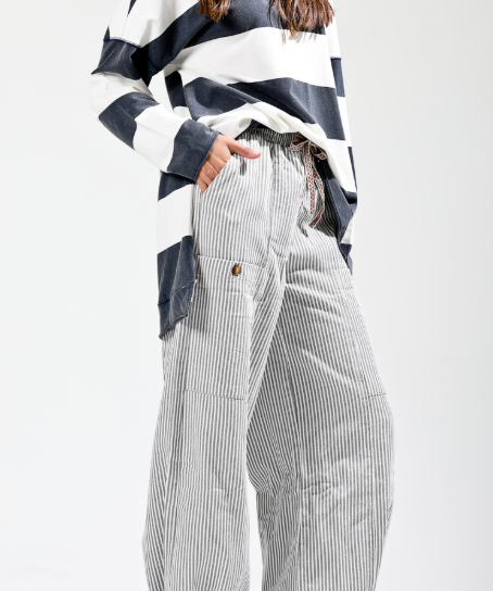 Person wearing a black and white striped shirt with high-waisted, wide-leg pants on a white background