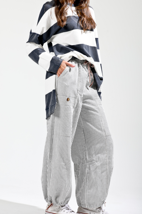 Person wearing a black and white striped shirt with high-waisted, wide-leg pants on a white background