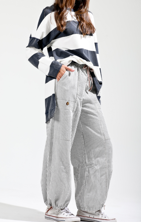 Person wearing a black and white striped shirt with high-waisted, wide-leg pants on a white background