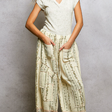 Woman wearing a white top and patterned beige pants against a gray background