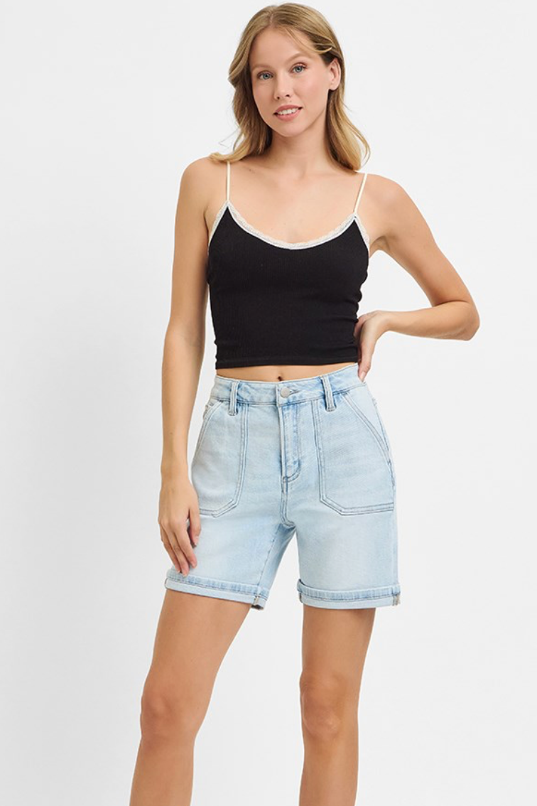 Woman wearing a black tank top and light blue denim shorts on a white background
