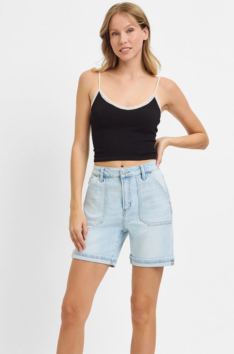 Woman wearing a black tank top and light blue denim shorts on a white background