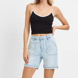 Woman wearing a black tank top and light blue denim shorts on a white background