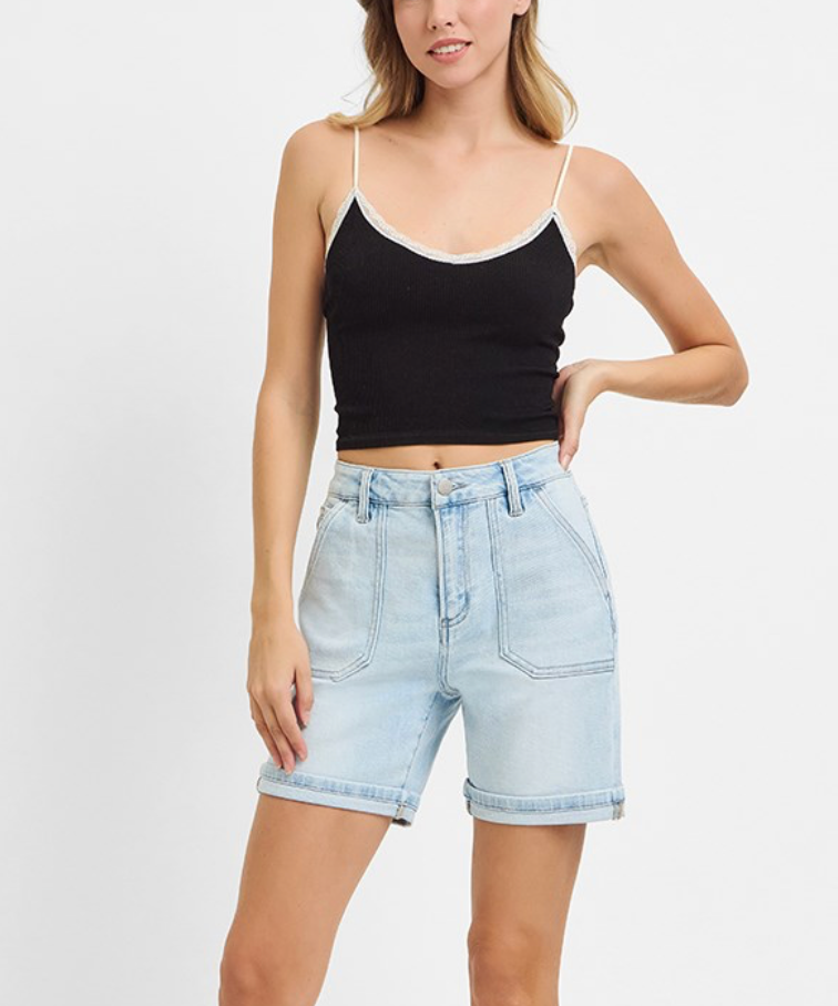 Woman wearing a black tank top and light blue denim shorts on a white background