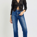 Woman wearing a black knit cardigan and blue jeans on a white background