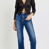 Woman wearing a black knit cardigan and blue jeans on a white background