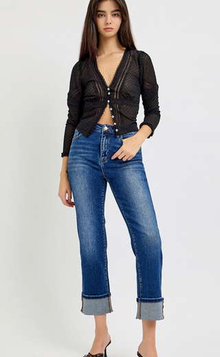 Woman wearing a black knit cardigan and blue jeans on a white background