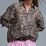 Person wearing a leopard print shirt and pink skirt on a gray background