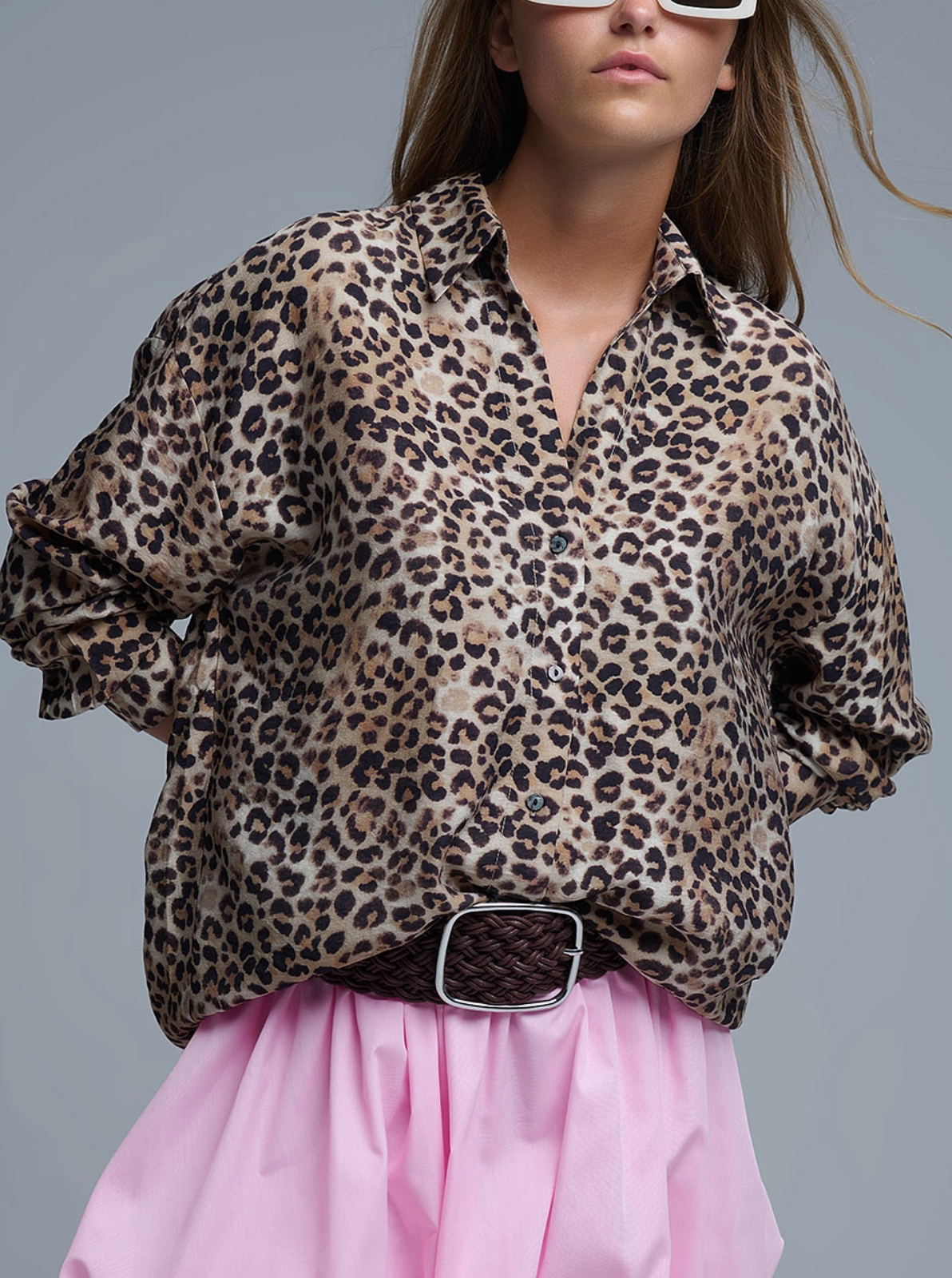 Person wearing a leopard print shirt and pink skirt on a gray background