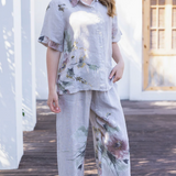 Woman wearing a floral outfit standing on a wooden deck.