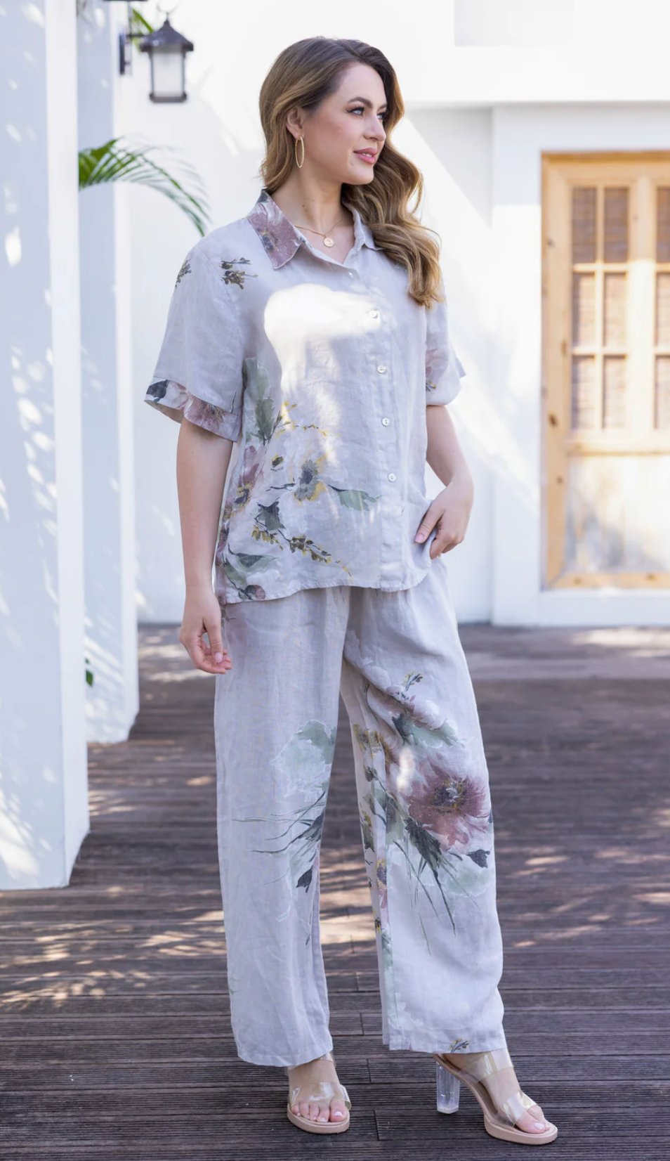 Woman wearing a floral outfit standing on a wooden deck.