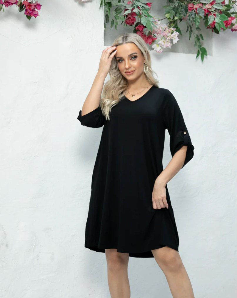 Woman wearing a black dress against a light background with floral decorations.