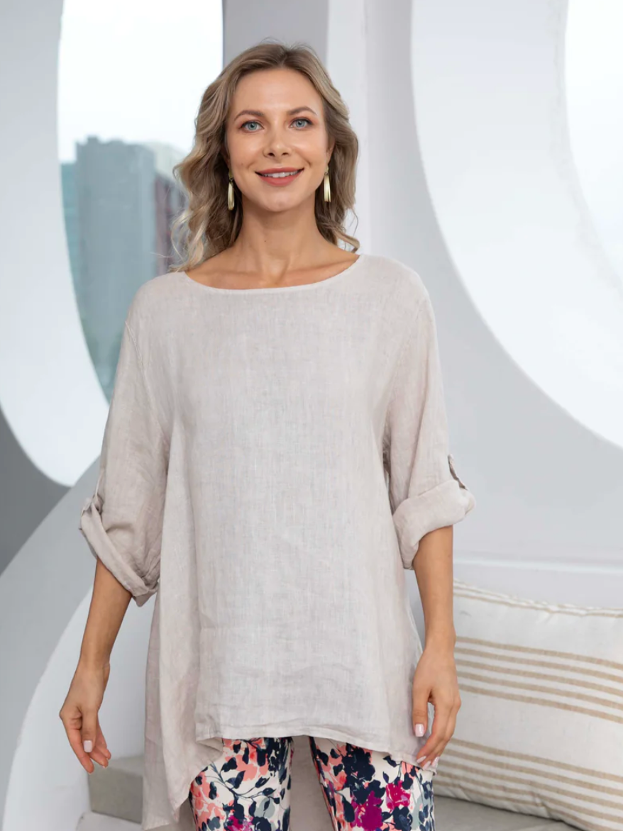 Woman wearing a beige top and floral pants in a studio setting
