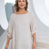 Woman wearing a beige top and floral pants in a studio setting