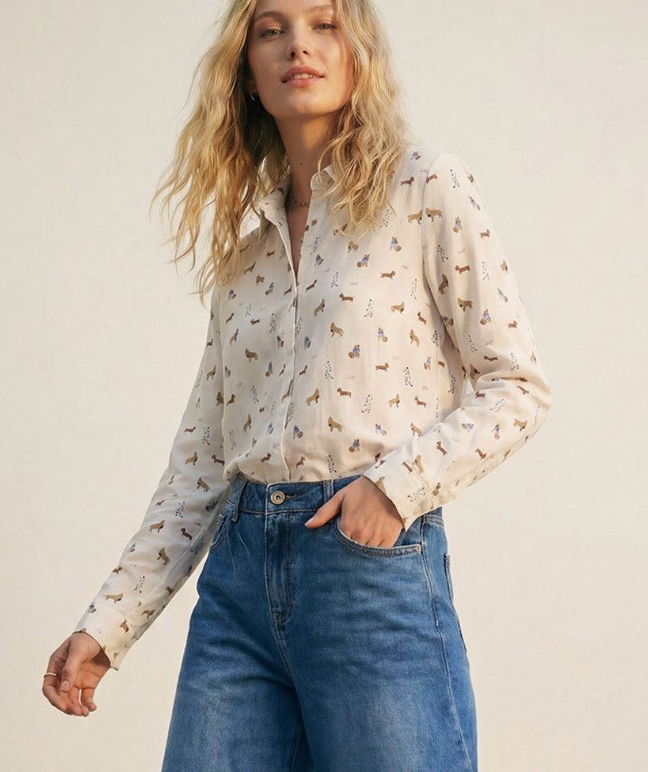 Woman wearing a patterned shirt and blue jeans against a plain background