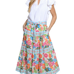 Woman wearing a white blouse and colorful floral skirt on a white background