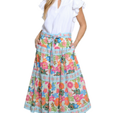 Woman wearing a white blouse and colorful floral skirt on a white background