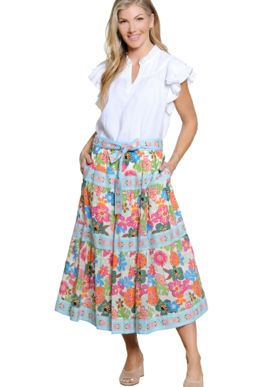 Woman wearing a white blouse and colorful floral skirt on a white background