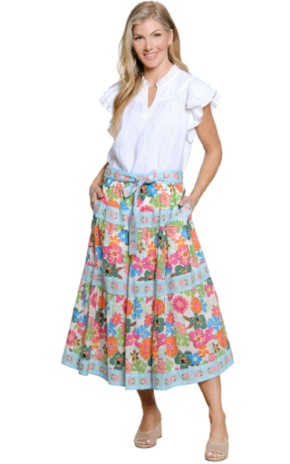 Woman wearing a white blouse and colorful floral skirt on a white background