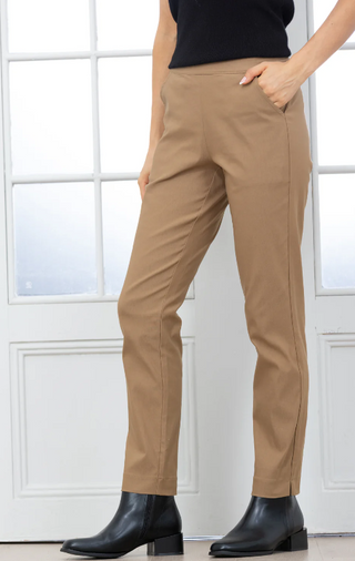 Person wearing beige pants and black boots in front of a white paneled wall.