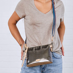 Person wearing a gray t-shirt and blue jeans with a snakeskin crossbody bag on a light gray background