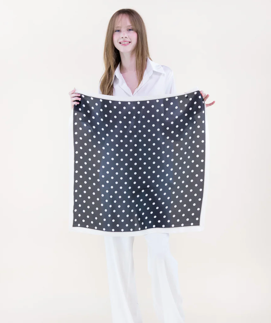 Woman holding a black and white polka dot fabric against a white background