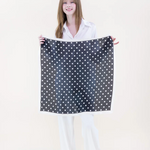 Woman holding a black and white polka dot fabric against a white background