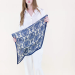 Woman holding a blue and white patterned scarf against a white background