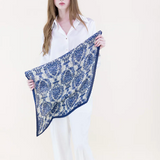 Woman holding a blue and white patterned scarf against a white background