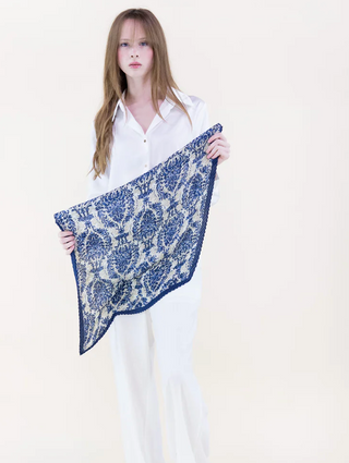Woman holding a blue and white patterned scarf against a white background
