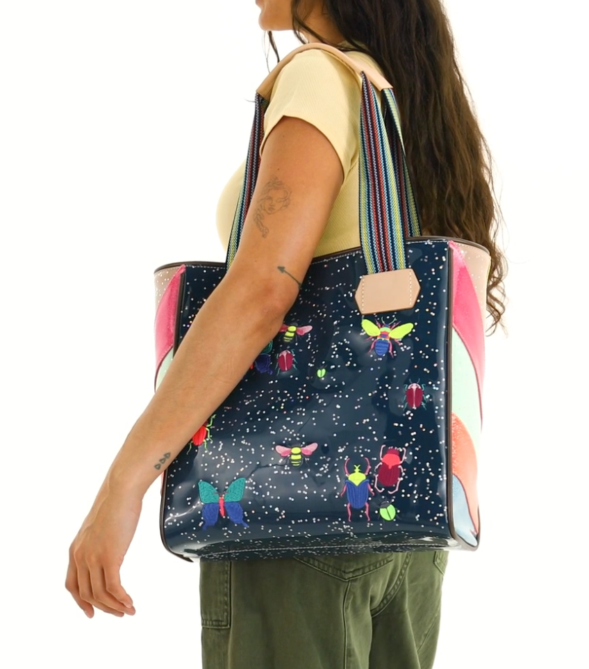 Person carrying a colorful tote bag with cartoon designs on a white background