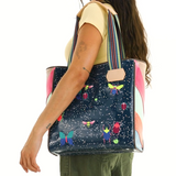 Person carrying a colorful tote bag with cartoon designs on a white background