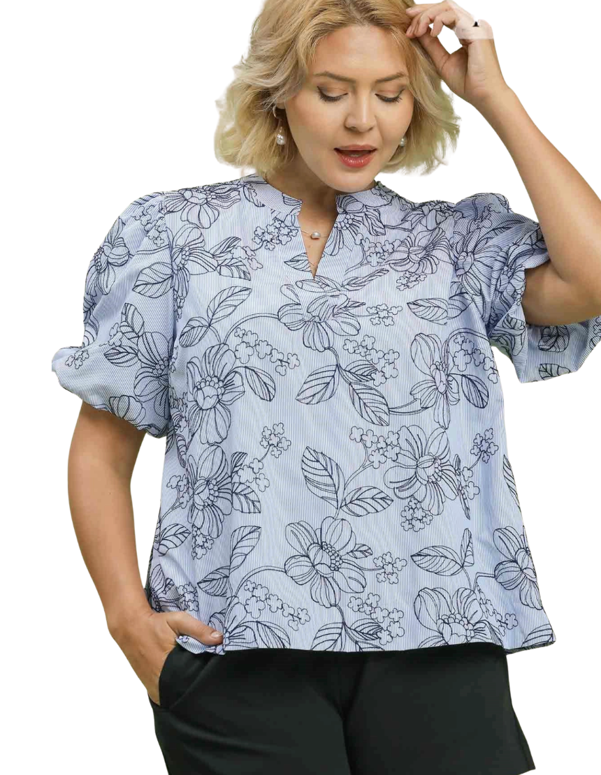 Woman wearing a light blue floral blouse with puffed sleeves on a white background