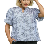 Woman wearing a light blue floral blouse with puffed sleeves on a white background